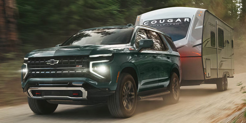 Dark green Chevrolet Tahoe Z71 towing a camper trailer.
