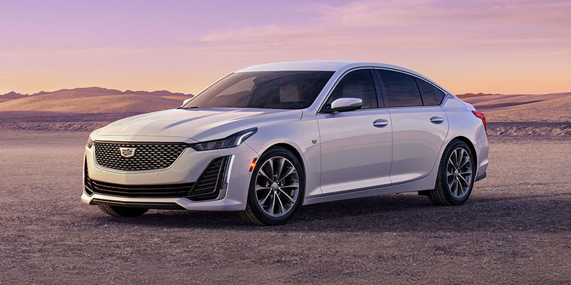 White Cadillac CT5 sedan parked in the desert at sunset.